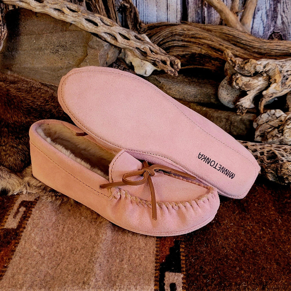 Pair of pink moccasins with pile lined interior, rawhide lace, and soft sole exterior.