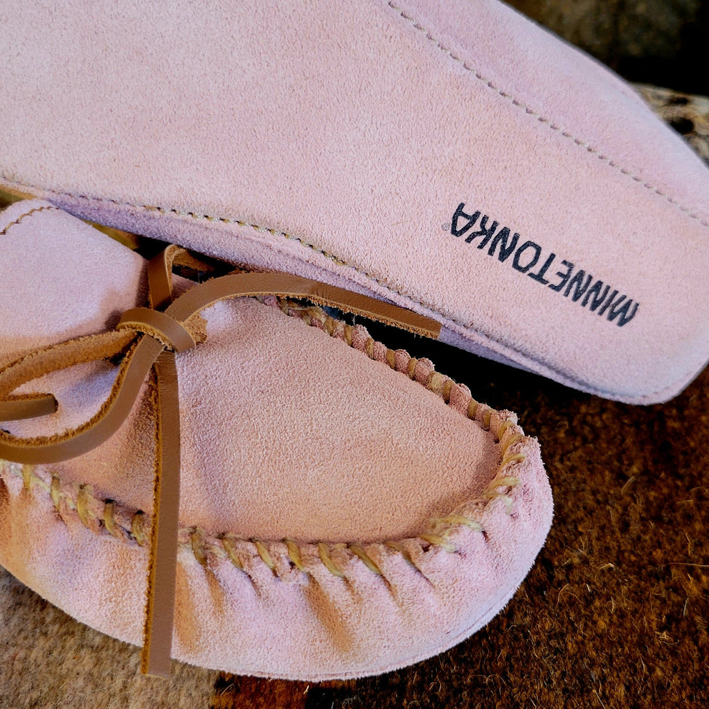 Pair of pink moccasins with pile lined interior, rawhide lace, and soft sole exterior.