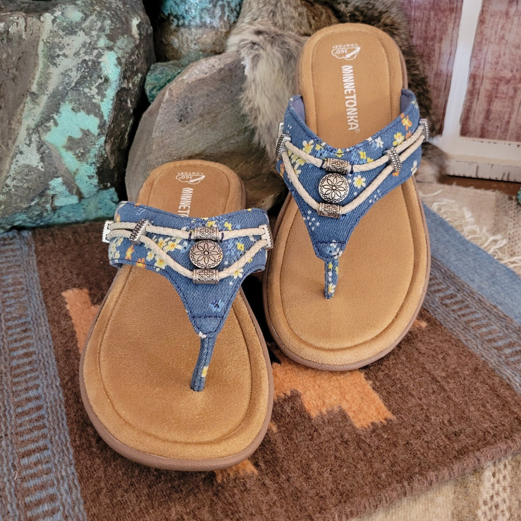 Floral denim sandal with braided strap and silver concho. Minnetonka branding on tan suede footbed.