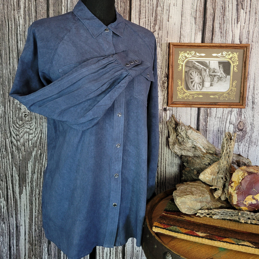 Denim colored long sleeve shirt with snap buttons, dual pockets, and blouse sleeves.