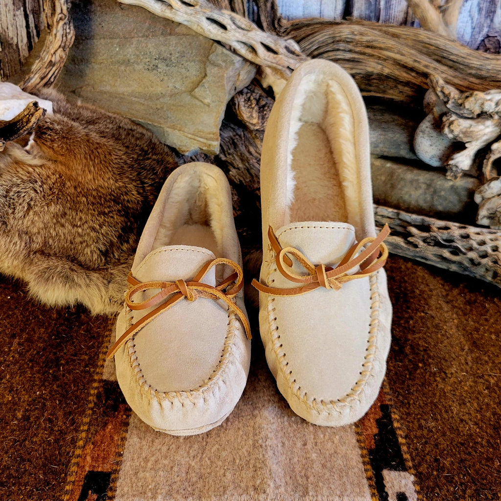Pair of cream colored moccasins with pile lined interior and rawhide laces.