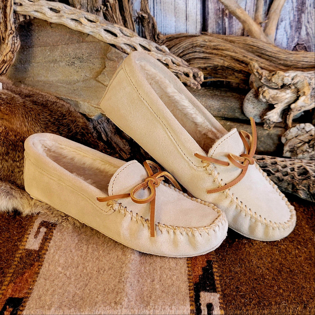 Pair of cream colored moccasins with pile lined interior and rawhide laces.