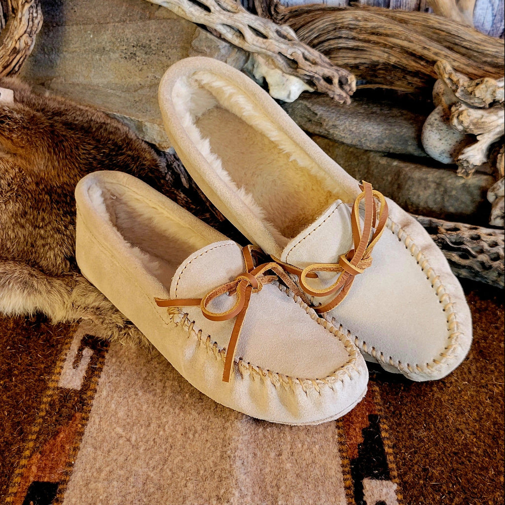 Pair of cream colored moccasins with pile lined interior and rawhide laces.