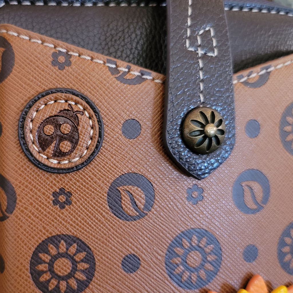 A small ladybug charm embroidered into the faux leather.