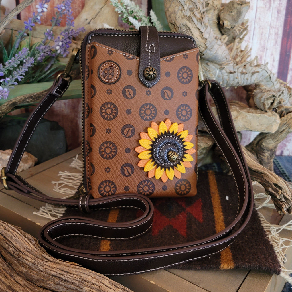 A brown faux leather crossbody bag displays a sunflower design with yellow and orange petals, accented by detailed stitching.