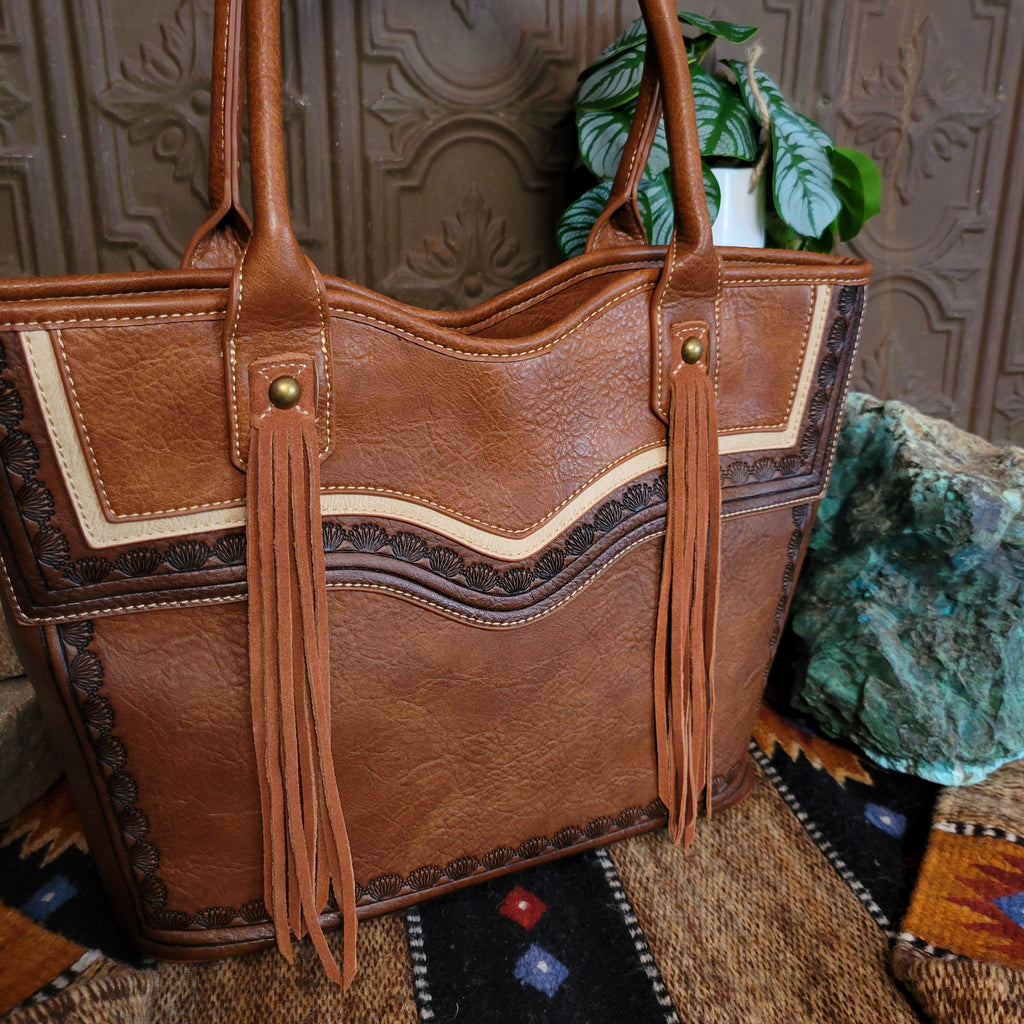 A close-up of the tricolor leather, tooled designs, and fringe on the front.