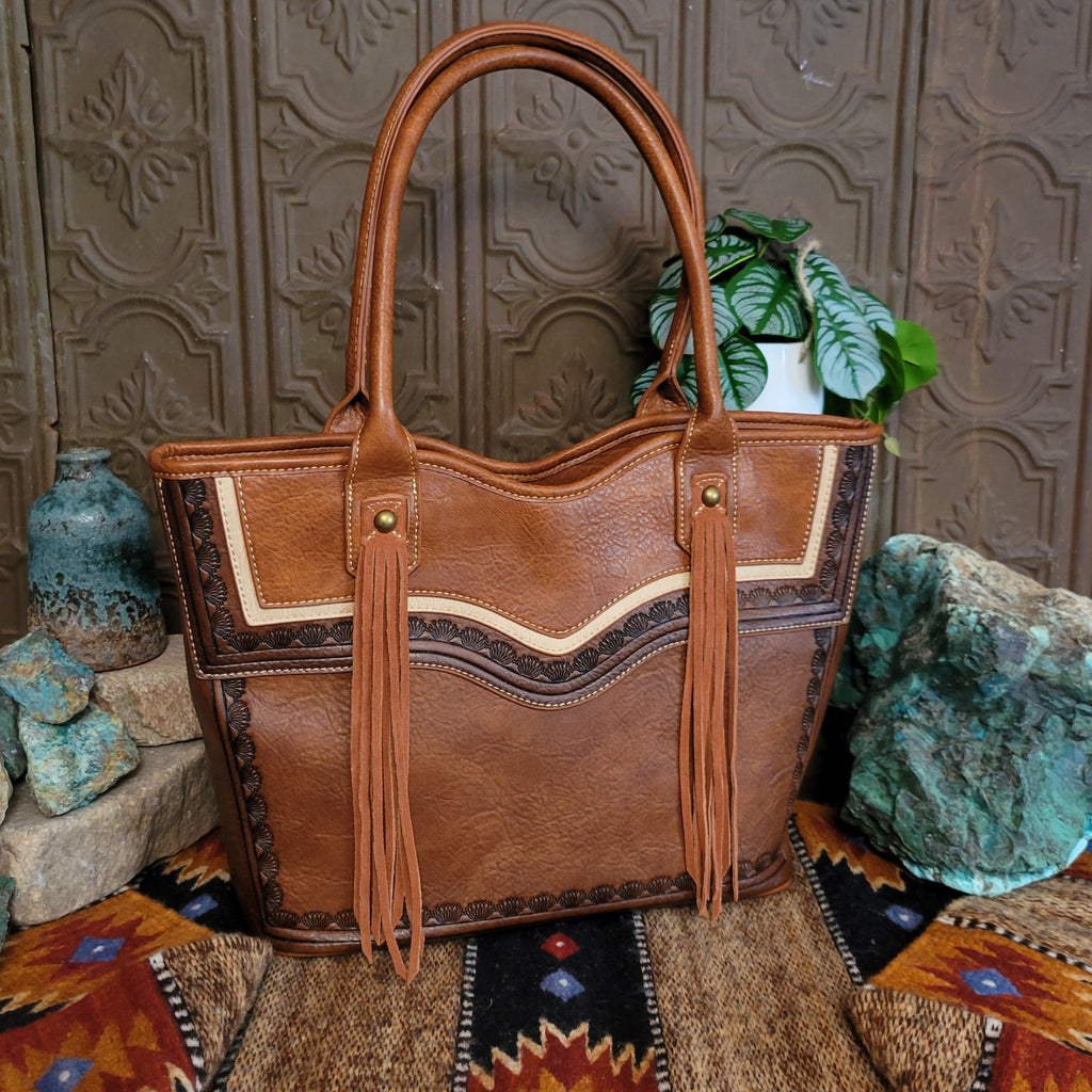 Brown leather purse with intricate tooling detail and fringe on the front.