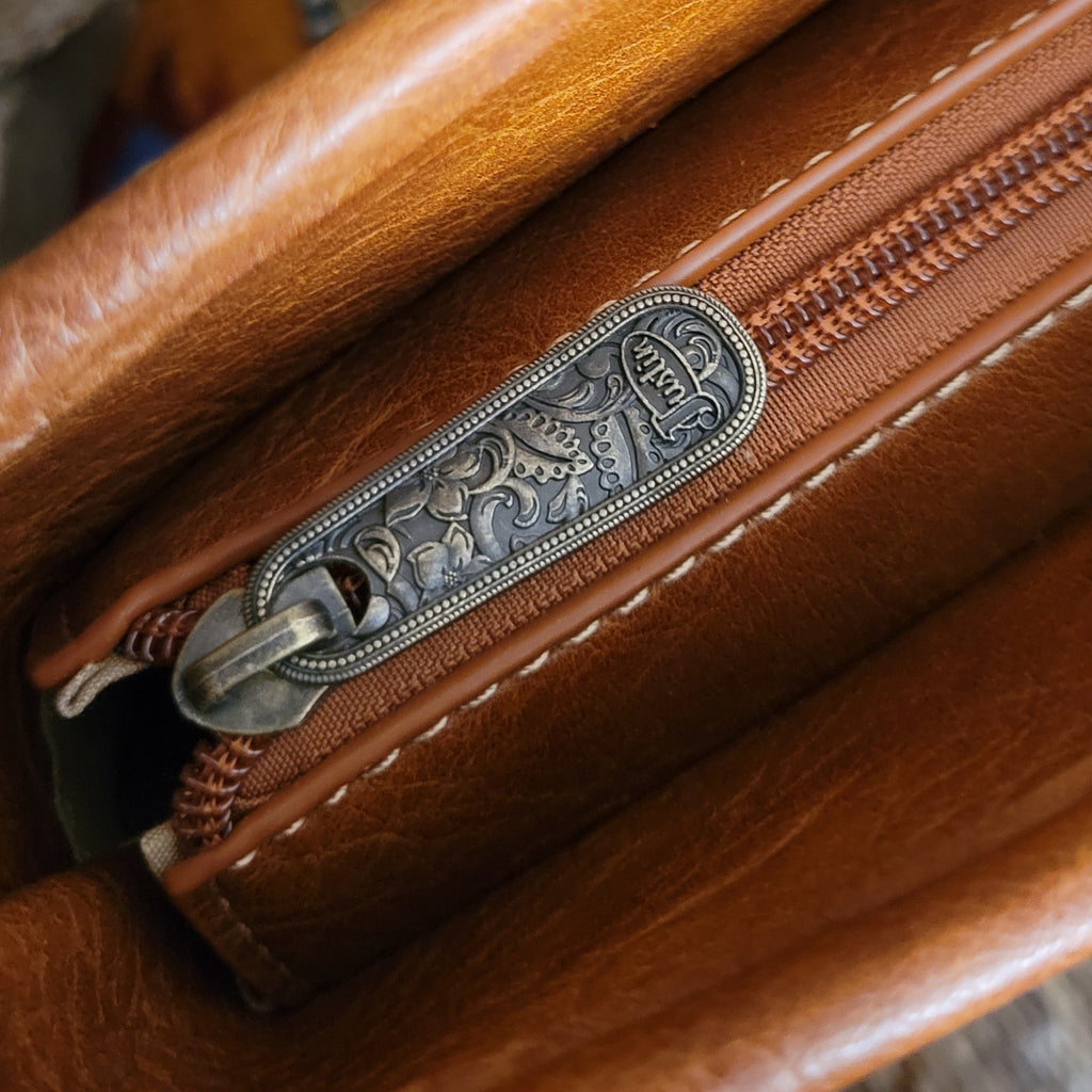 A close-up view of the zipper with ornate details and brand name.