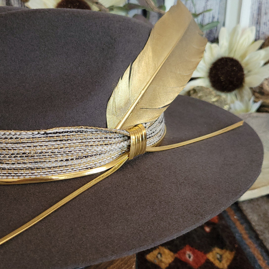A close-up view of the gold feather, decorative band, and gold cords.