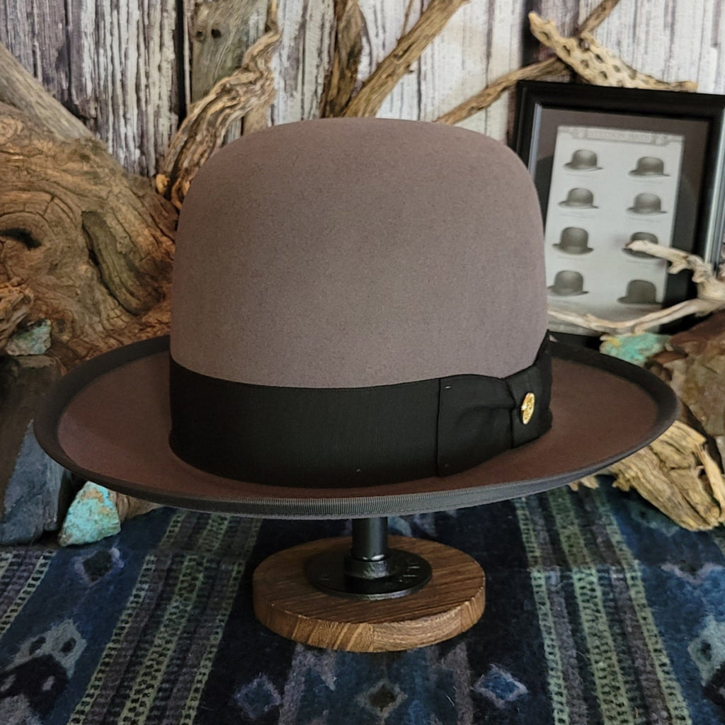 Gray wool hat with large black band and bow featuring a gold concho.