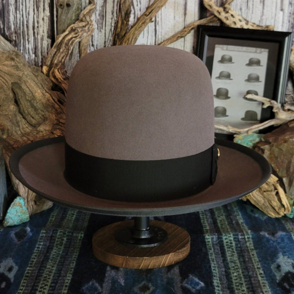 Gray wool hat with large black band and bow featuring a gold concho.