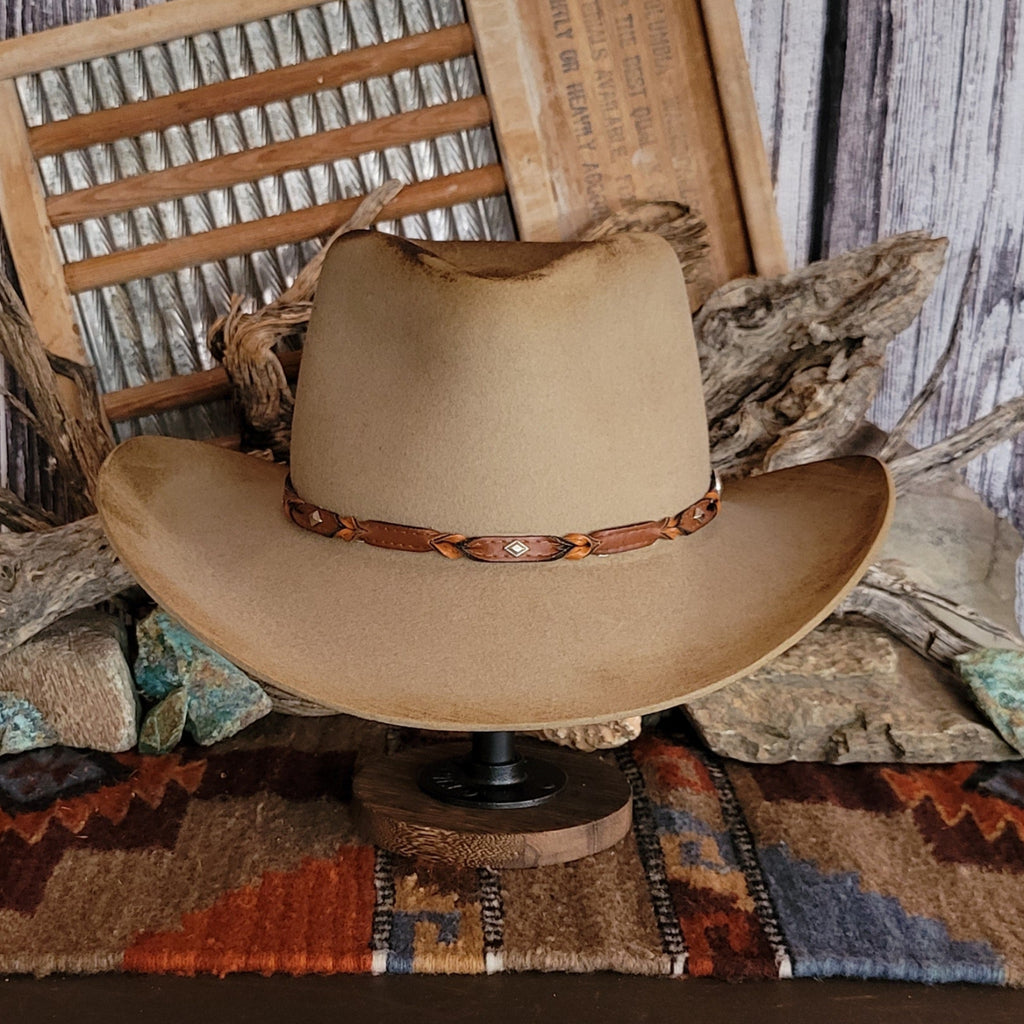 Brown cowboy hat with distressed appearance and a leather hat band.