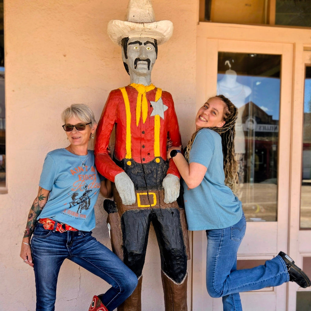 Two Women modeling tee shirt with wooden cowboy.